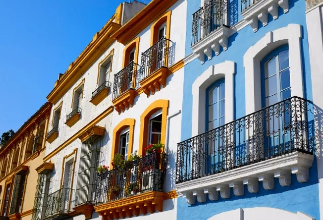 Fachadas tradicionales con balcones de forja y molduras en ocre y blanco en una calle del centro histórico