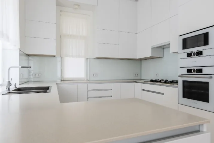 Cocina blanca con muebles lacados sin tiradores y encimera de cuarzo blanca en una vivienda de Las Gabias
