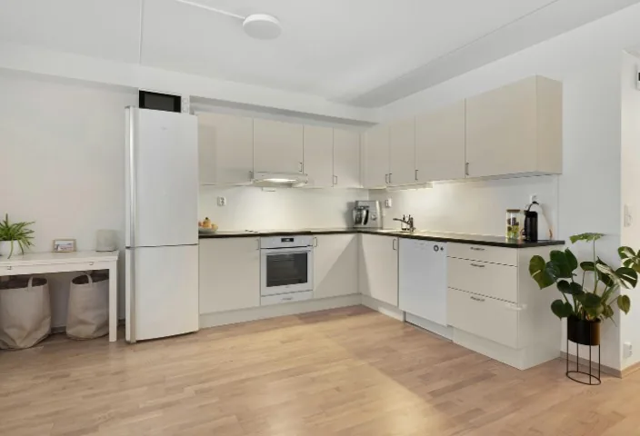 Cocina blanca reformada con muebles altos y suelo de madera